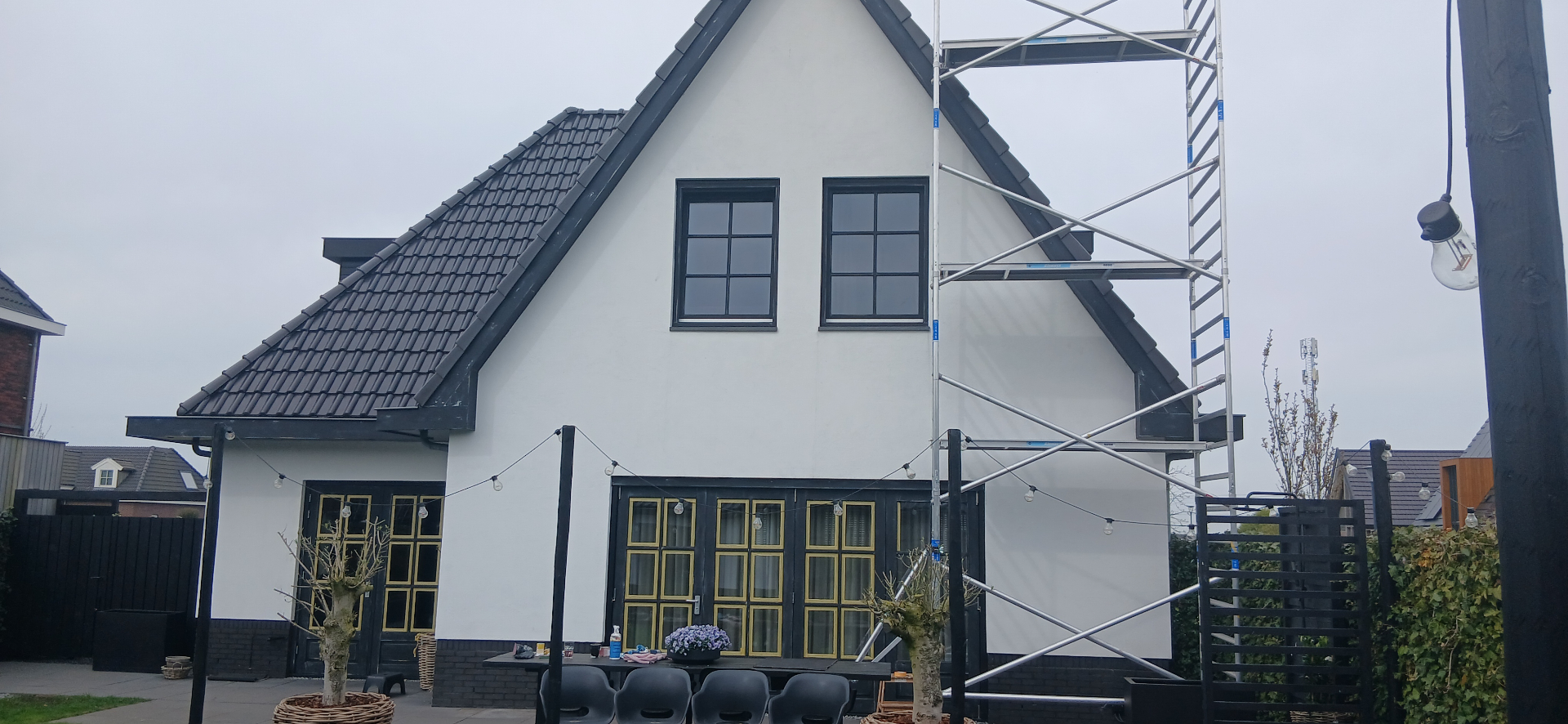 Wit geschilderde woning met puntdak en houten kozijnen