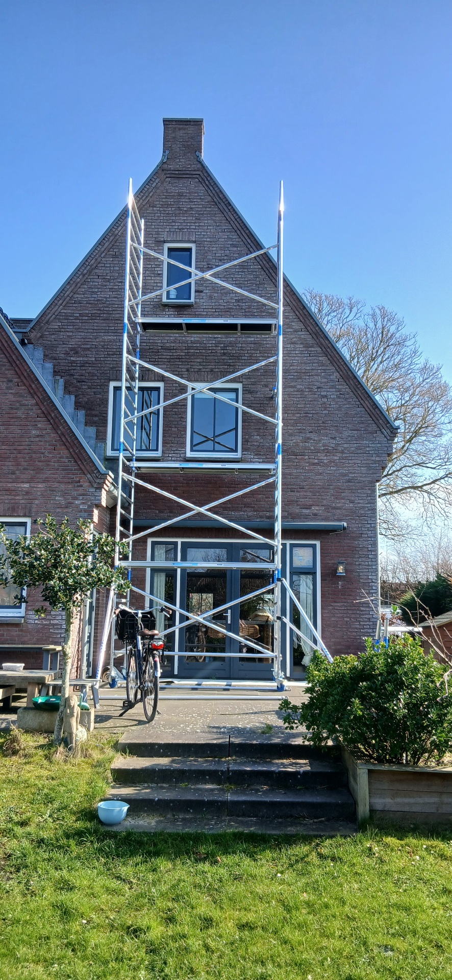 Buitenschilderwerk van een bakstenen woning met witte kozijnen